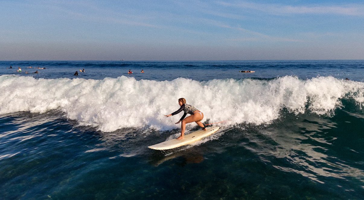 Beginner surfer riding a wave in Bali, Indonesia.