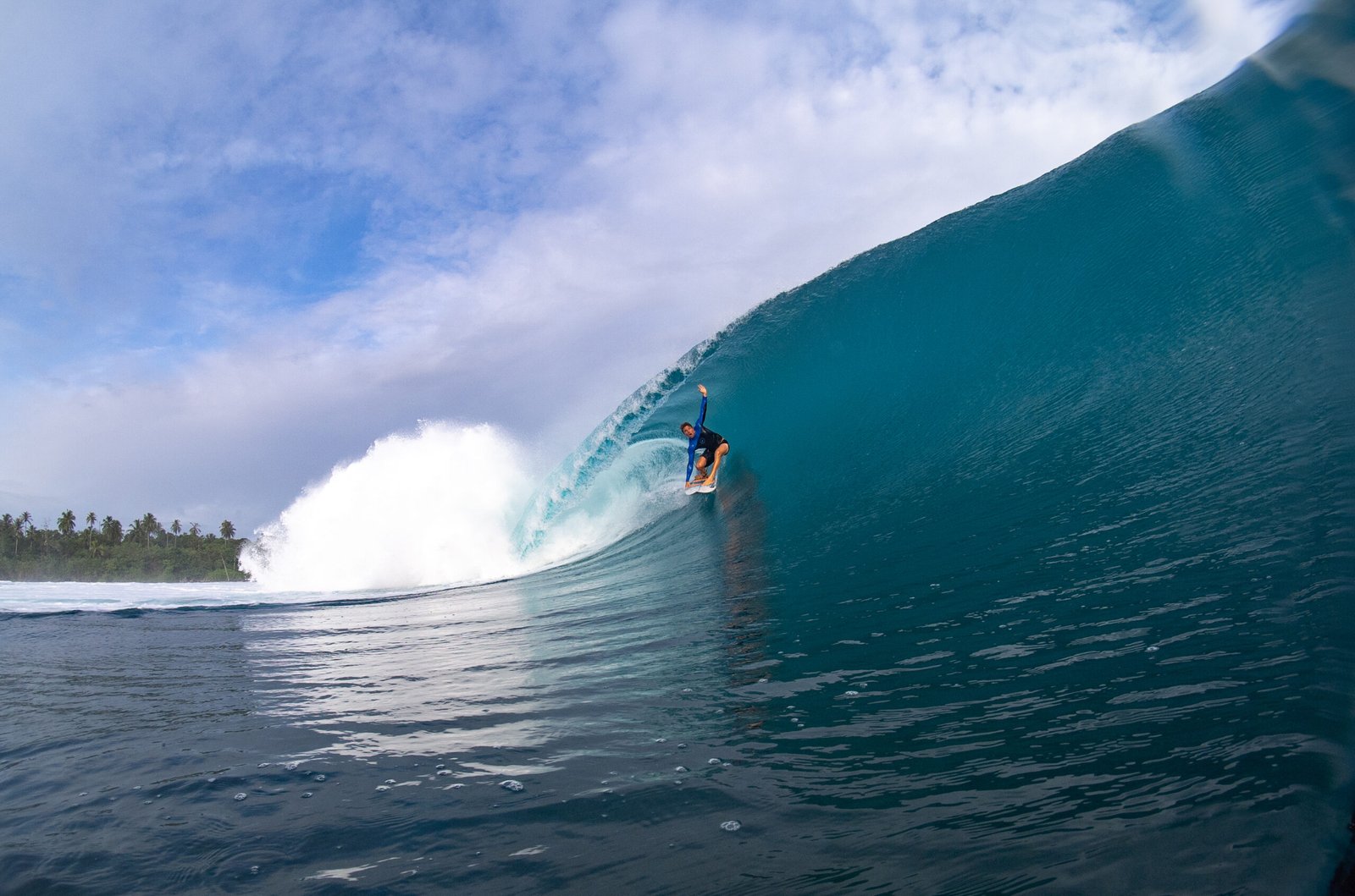Surfer riding a large barreling wave in Indonesia.